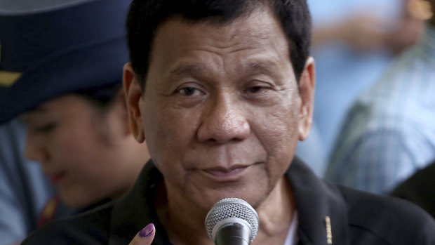 President Rodrigo Duterte shows his forefinger with an indelible ink to prove that he has voted in the country's midterm elections in his hometown of Davao.