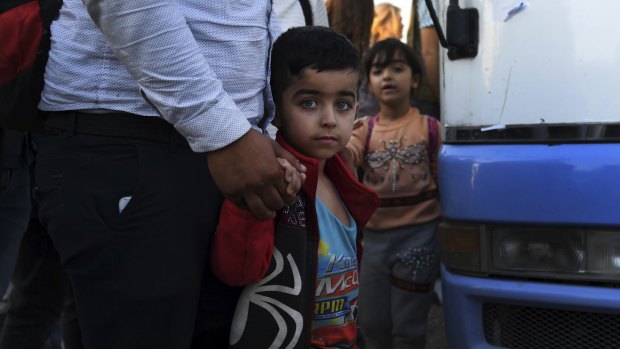 A Syrian boy holds his father's hand after disembarking from one of the buses that brought 784 Syrian refugees to Bardarash Refugee Camp in Iraqi Kurdistan.