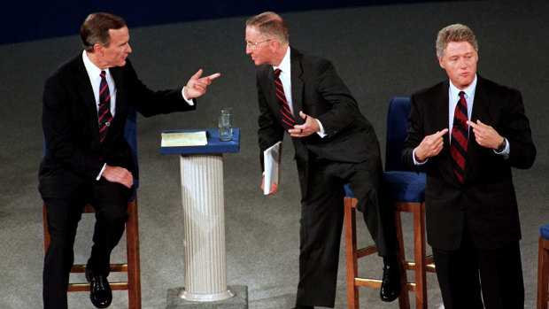 President George H.W. Bush, left, talks with independent candidate Ross Perot as Democratic candidate Bill Clinton stands aside at the end of their second presidential debate in 1992.  