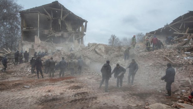 People remove debris at the site of a military base building that, according to the Ukrainian ground forces, was destroyed by an air strike, in the town of Okhtyrka in the Sumy region.