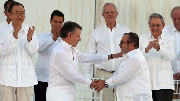 Colombian President Juan Manuel Santos, front left, and the top FARC commander, Rodrigo Londono, known by the alias Timochenko, shake hands after signing the 2016 peace agreement to end 50 years of conflict.