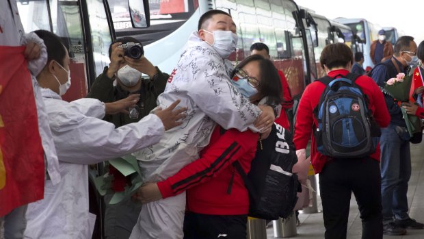 A medical worker, in red, embraces a colleague as she prepares leave Wuhan's main airport on Wednesday.