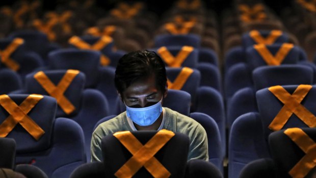 A man checks his mobile phone as he sits amid physical distancing markers prior to the start of a movie at the recently reopened CGV Cinemas theatre in Jakarta, Indonesia, last month. 