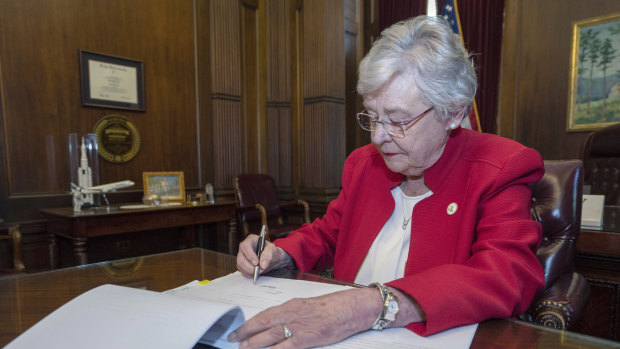 This photograph released by the state shows Alabama Governor Kay Ivey signing a bill that virtually outlaws abortion in the state on Wednesday.