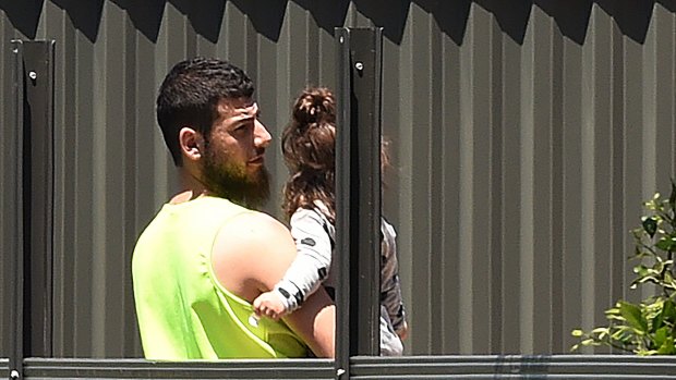 Mehmet Biber carrying his daughter in the backyard of the family home in Merrylands.