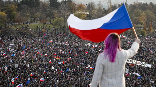 Days earlier, a woman waves a Czech flag from a roof as people take part in a large anti-government protest in Prague.
