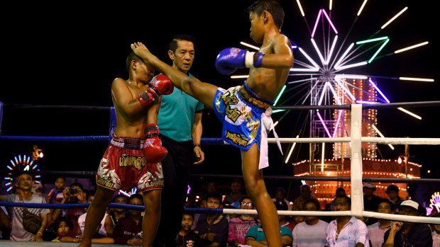 Mauy Thai fighter Samsun, 11, (left) takes a kick to the face during a bout.