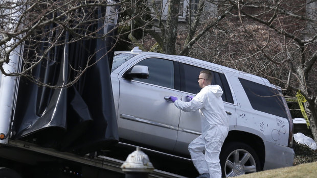 Crime scene investigators load a car that appears to have been checked for fingerprints onto a truck outside Cali's home.