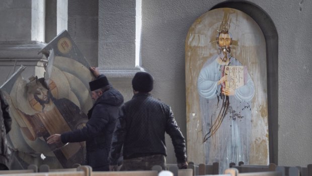 Men lift an icon in the Holy Saviour Cathedral damaged by shelling during a military conflict, in Shushi, in the self-proclaimed Republic of Nagorno-Karabakh.