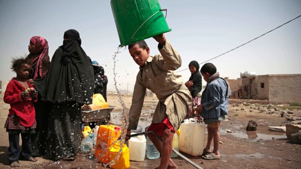 A boy rinses a bucket as he and others collect water in war-torn Yemen. 