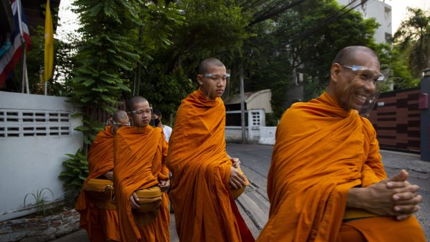 Buddhist monks wear face shields while collecting alms during a partial lockdown in Bangkok on Monday.