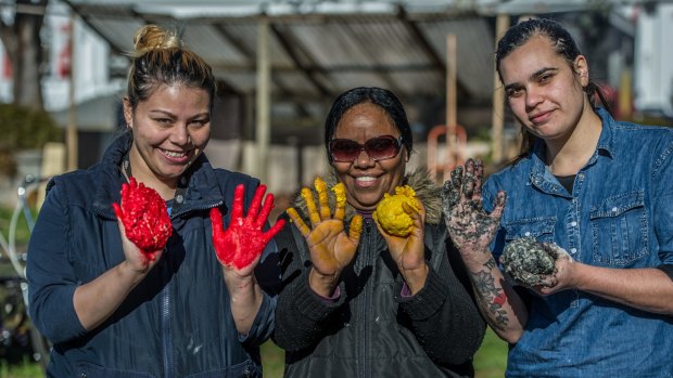 Amber Jarrett, Sylvia Rosas and Elizabeth Mitchell mixing dough in the colours of the Aboriginal flag at the damper cook-off during NAIDOC Week 2017.
