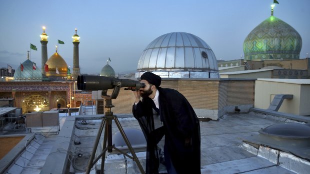 A cleric looks through binoculars to sight the new moon that signals the start of the Islamic holy fasting month of Ramadan at the shrine of the Shiite Saint Imam Abdulazim.