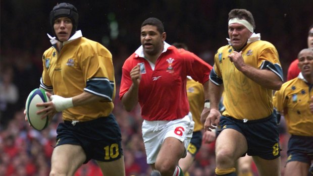 Australia's Stephen Larkham, left, charges with the ball pursued by Welsh player Colin Charvis, centre, during the Rugby World Cup Quarter final at the Millennium Stadium in  Cardiff, Wales on October 23, 1999.