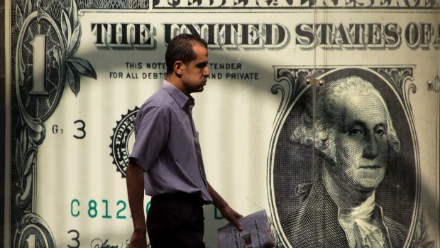 A man walking past a currency exchange office in Cairo. The greenback’s status as the world’s reserve currency is in danger as the the world's largest economy is in turmoil.