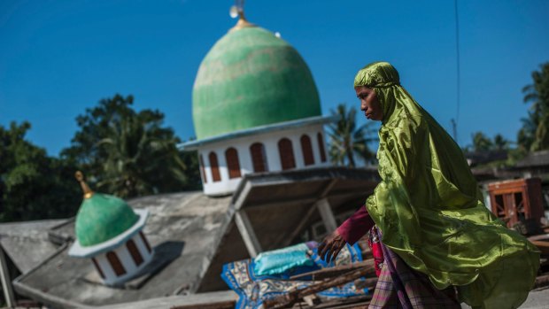 A Muslim woman walks past a mosque collapsed during the August 9 earthquake in Gangga, Lombok Island.