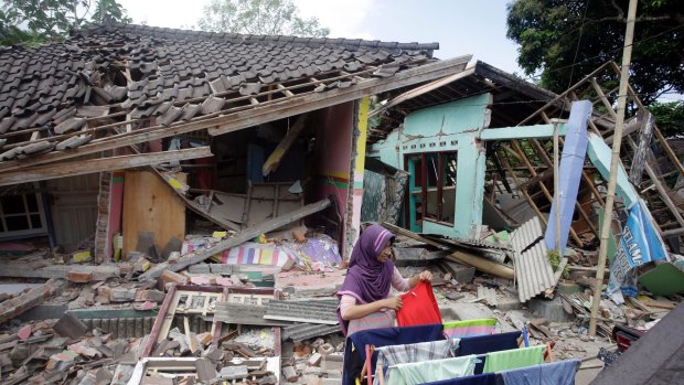 A woman dries her laundry in front of her home shortly after the quake in West Lombok.