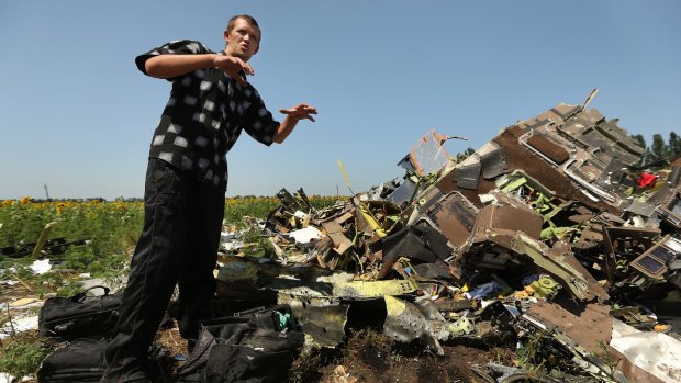 Donetsk People's Republic sniper Eugene Lukovkin, aged 30, stands among the pilots' bags at one of the sites where he witnessed the front section of Malaysian flight MH17 crashing.