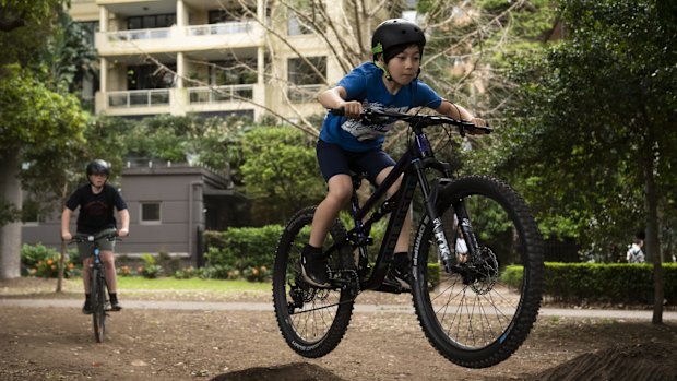 A group of kids having fun jumping their bikes in Rushcutters Bay Park.