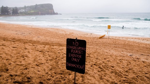 A sign on Avalon Beach asking the public not to congregate on the beach due to the COVID outbreak.