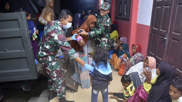 Indonesian soldiers help Rohingya women and children at a temporary shelter after their boat landed in Pidie, Aceh province in December.