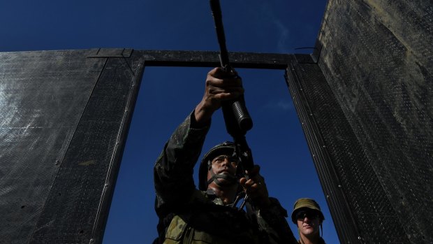 Private Brodie Smith (right)  observes a Filipino marine as he enters a mock building during training.