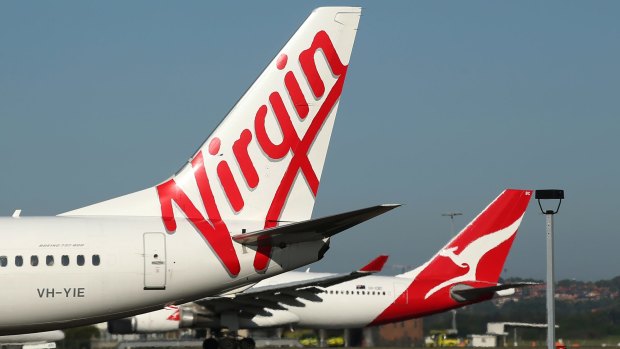 The Virgin Australia Holdings Ltd. logo, left, and Qantas Airways Ltd. logo are displayed on the tails of aircraft at Sydney Airport in Sydney, Australia, on Monday, Feb. 8, 2016. Virgin Australia is scheduled to announce half-year earnings on Feb. 11. Photographer: Brendon Thorne/Bloomberg