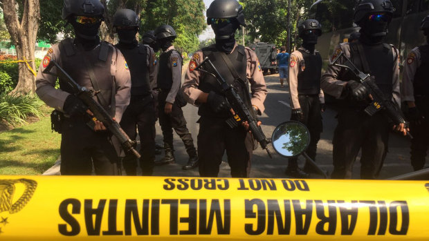 Police officers stand guard near the site where an explosion went off at Santa Maria church in Surabaya, East Java, Indonesia.