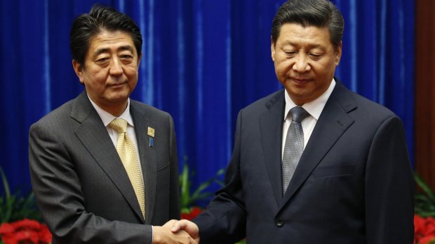 Uncomfortable: China's President Xi Jinping (right) shakes hands with Japan's Prime Minister Shinzo Abe in 2014.