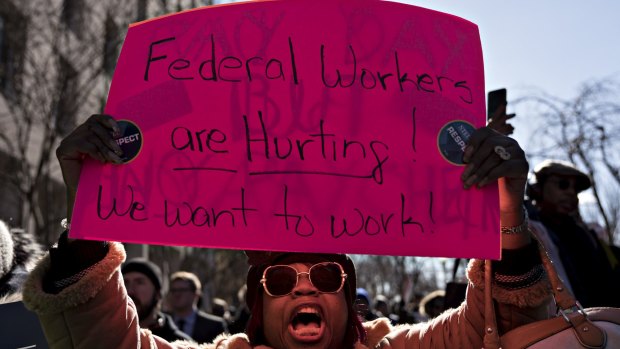 A furloughed federal employee holds a sign during a rally to end the partial government shutdown.