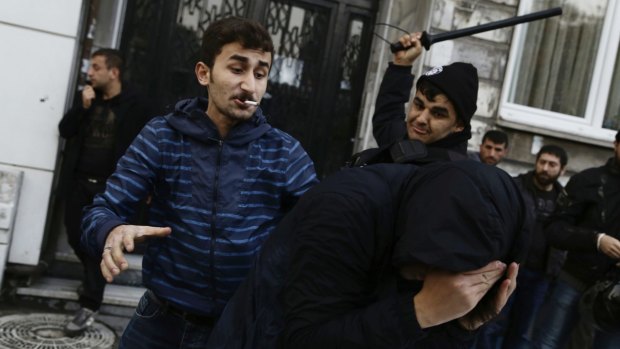 A man in plain clothes, left, and a uniformed security officer beat a protester demanding freedom for detained  MPs of the pro-Kurdish People's Democratic Party  in Istanbul in 2016.