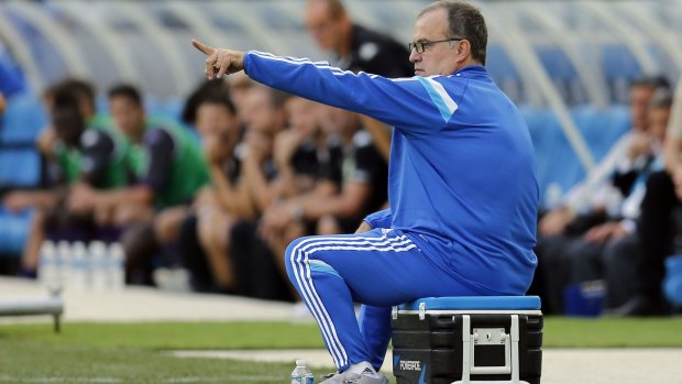 The former Marseille boss sits on an esky or bucket on the sideline. 