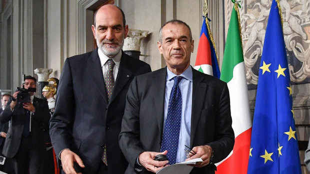 New premier-designate Carlo Cottarelli, right, arrives to address the media after meeting with Italian President Sergio Mattarella.