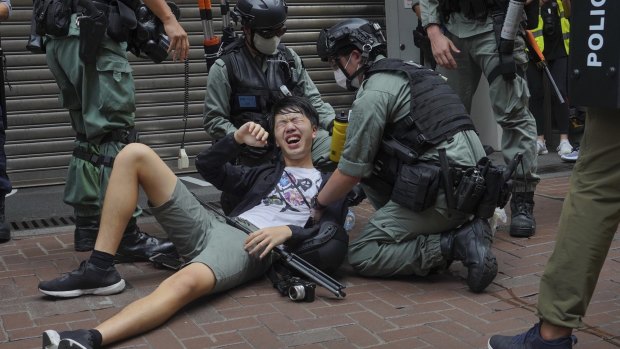 A reporter falls after being sprayed with pepper spray by police during a protest in Hong Kong in July.