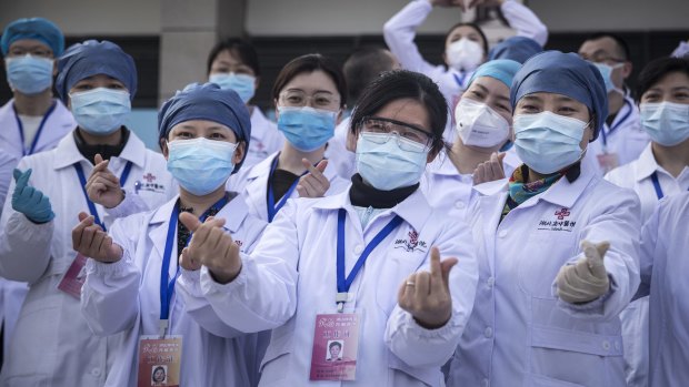 Medical professionals pose for photos as the last batch of COVID-19 patients are discharged from Wuchang Fang Cang makeshift hospital in Wuhan in March.