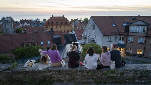 Limited to groups of eight: people sit along a street in the town of Visby in Gotland, Sweden. 