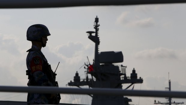 A Chinese People's Liberation Army navy personnel stands guard on their Jiangkai II class vessel, CNS Yulin, during a display of warships in Singapore.