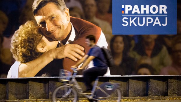 A cyclist rides past a campaign poster of Slovenian President Borut Pahor, in Ljubljana.