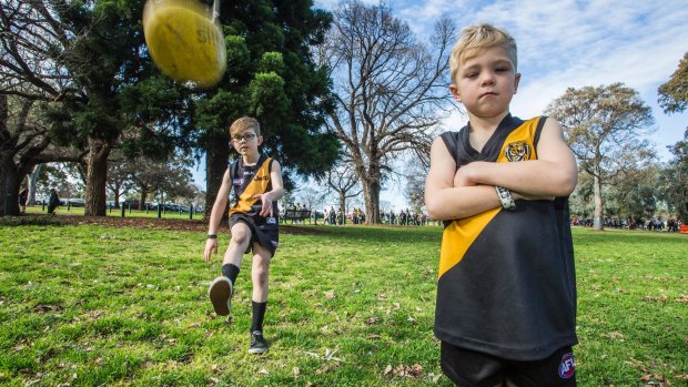 Hendrix, 8, kicks the ball while his brother Tyler stands by as they wait to go into the MCG on Saturday.