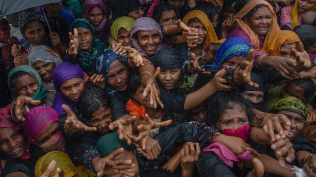 Rohingya Muslim women, who crossed over from Myanmar into Bangladesh, stretch their arms out to collect sanitary products distributed by aid agencies near Balukhali refugee camp, Bangladesh.