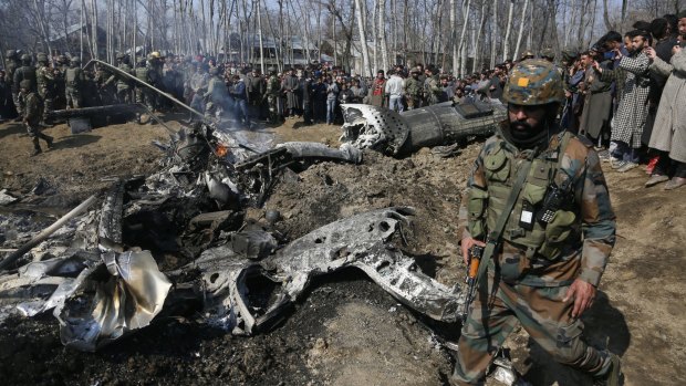 An Indian solider walks past the wreckage of an Indian aircraft after it crashed in the outskirts of Indian controlled Kashmir.