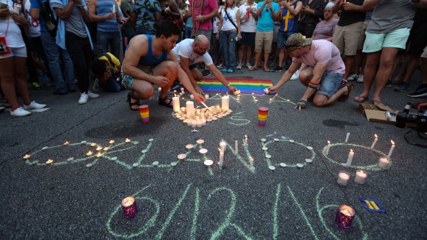 People light candles as members and supporters of the LGBT community gather for a vigil following a fatal 2016 shooting at a Pulse Orlando nightclub in Orlando, Sunday.