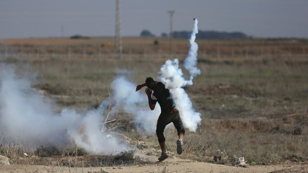 A Palestinian protester throws back a teargas canister fired by Israeli soldiers during clashes on the border with Gaza.