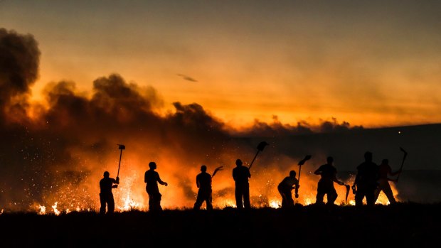 Firefighters work on a wildfire on Winter Hill near Bolton, England in June 2018.