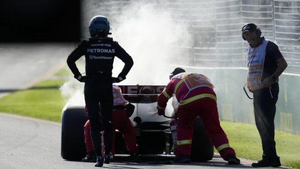 Mercedes driver George Russell (left) watches as course marshals extinguish an engine fire in his car during the grand prix.