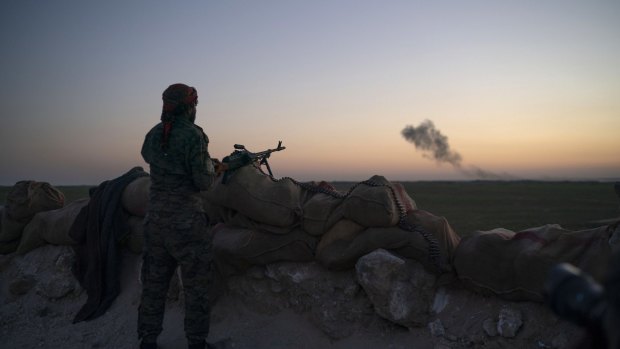 A US-backed fighter looks as smoke billows after an airstrike on territory still held by Islamic State militants outside Baghouz, Syria, in February. US President Donald Trump has said IS has now been defeated.
