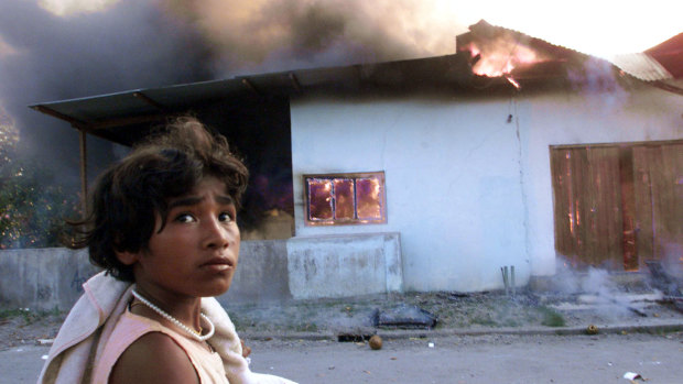 September 1999: A girl walks by a burning house in Dili, East Timor, two days before the arrival of Australian peacekeeping troops.