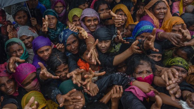 Rohingya Muslim women, who crossed over from Myanmar into Bangladesh, stretch their arms out to collect sanitary products.