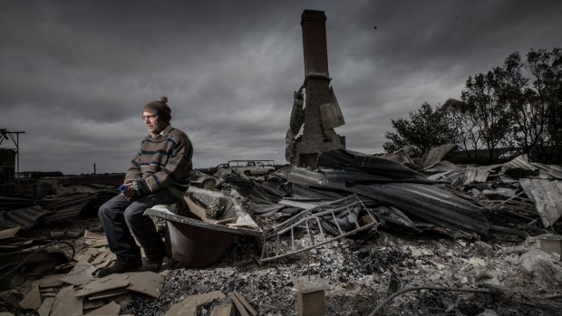 Angus McGillivery sits in the ruins of his Coyles road home near Terang after a bushfire ripped through the area. 