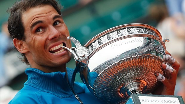 Eleven-times French Open winner Spain's Rafael Nadal bites the trophy.
